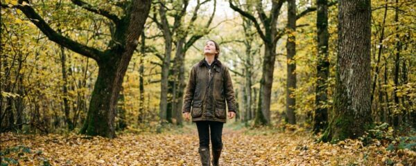 Futur acquéreur parcourant une allée forestière de chênes en observation du domaine